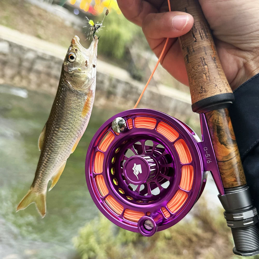 Purple enclosed fly reel in use beside a trout stream