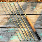Six bamboo-tan carbon fiber rod sections with green wraps, cork grip and black reel seat